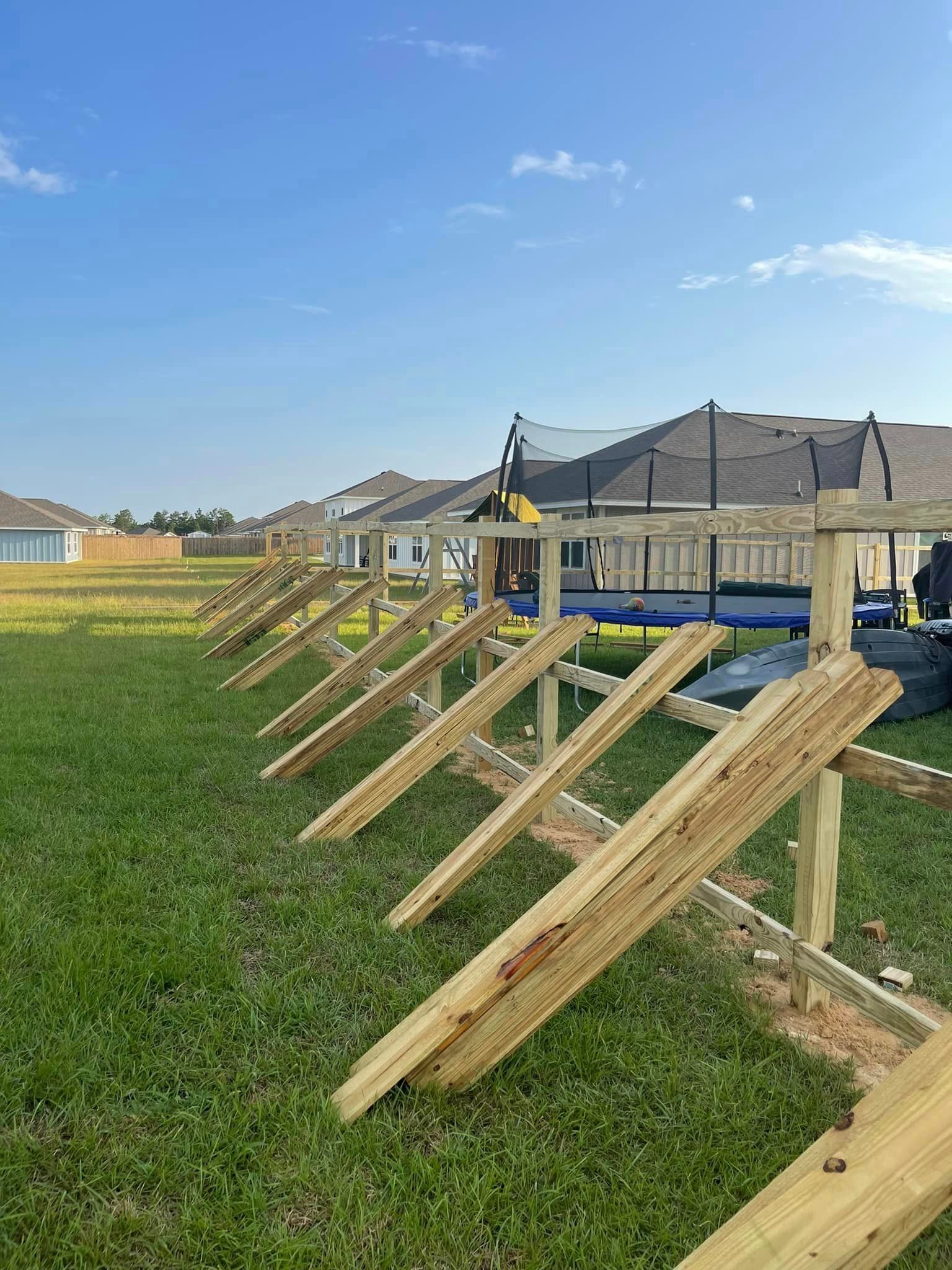 A wooden fence is being built in a grassy field.