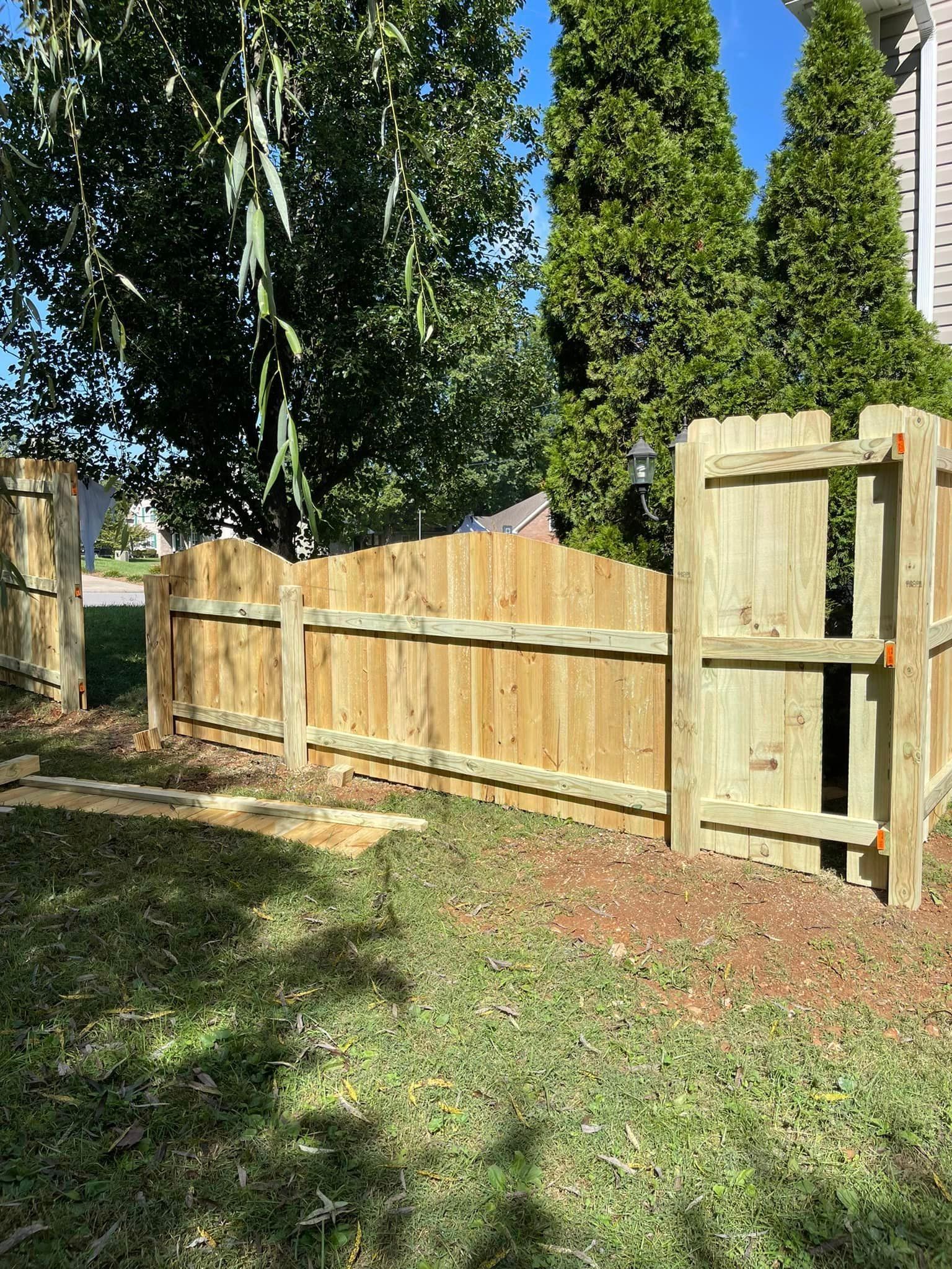 A wooden fence with a gate in the backyard of a house.