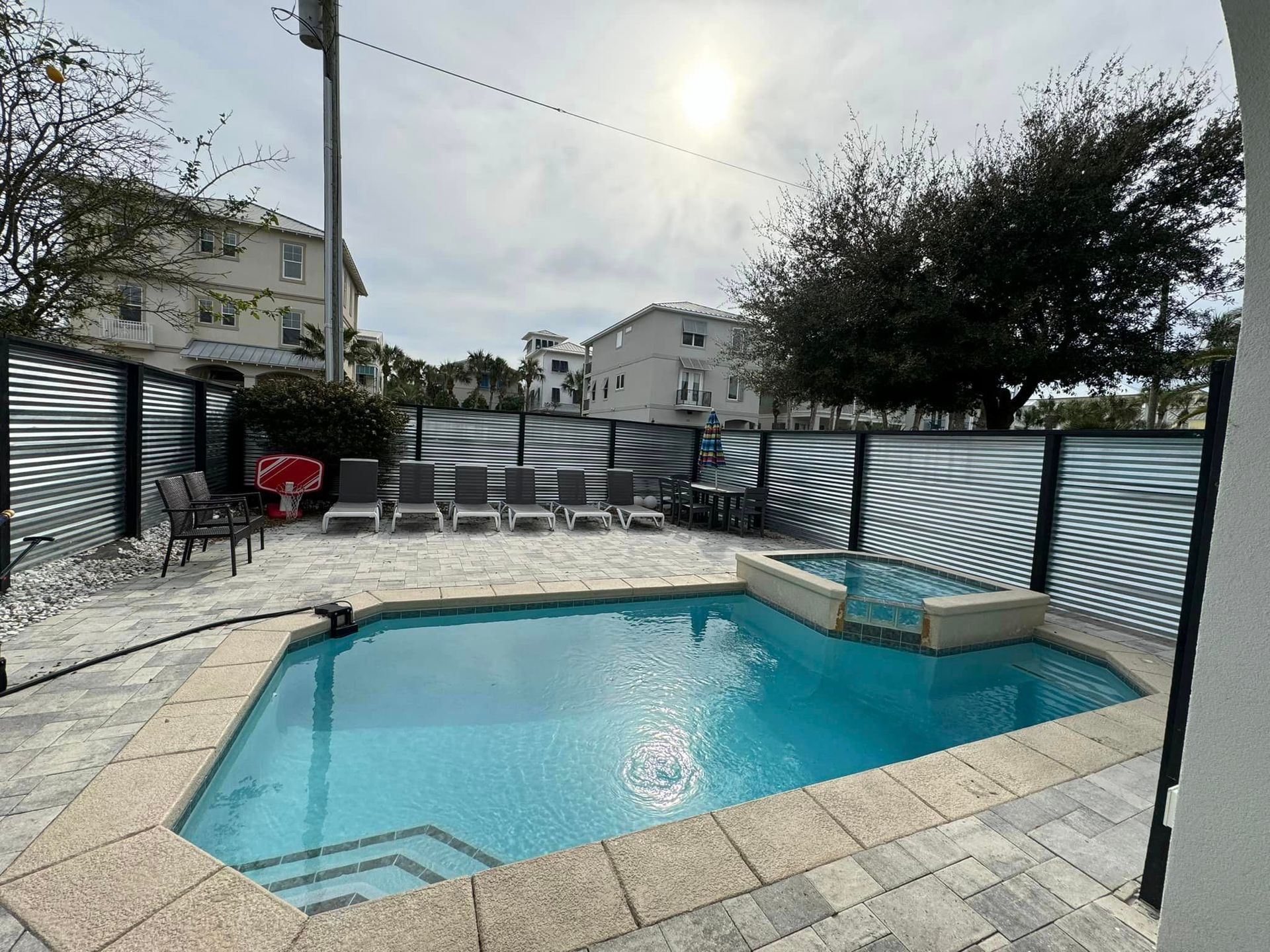 A large swimming pool is surrounded by chairs and a fence.