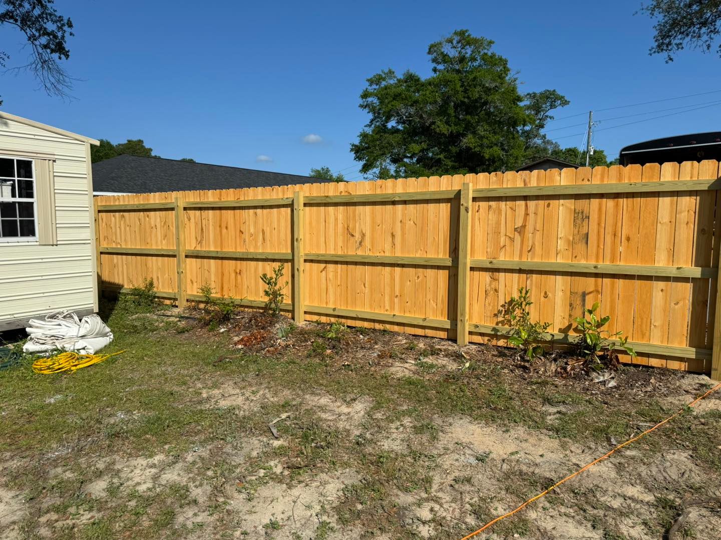 A wooden fence is in the backyard of a house.