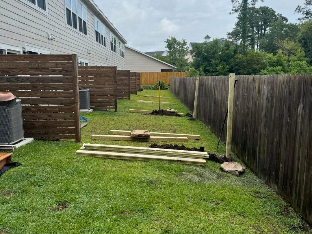 A wooden fence is being built in the backyard of a house.