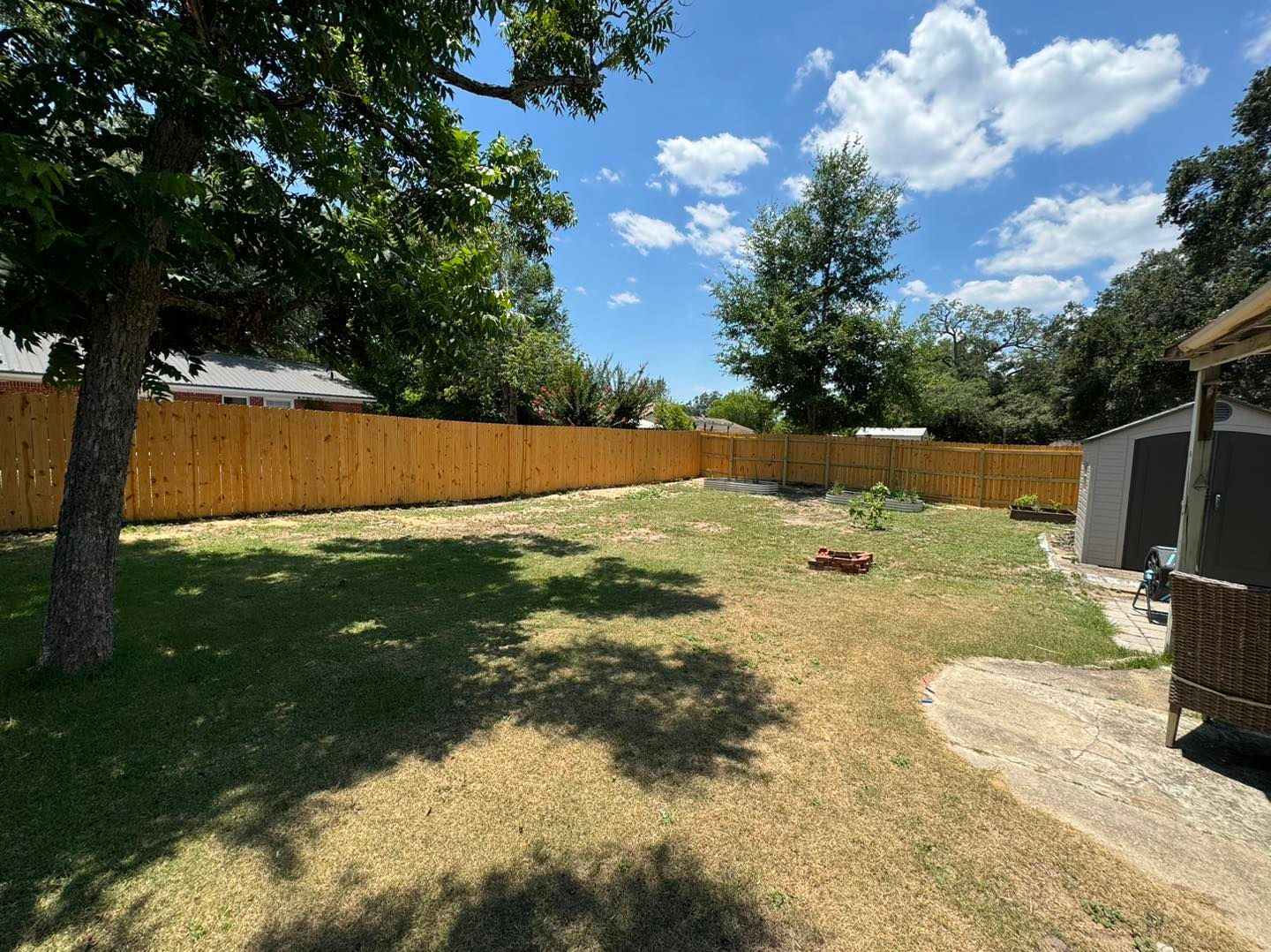 A backyard with a wooden fence and a fire pit.