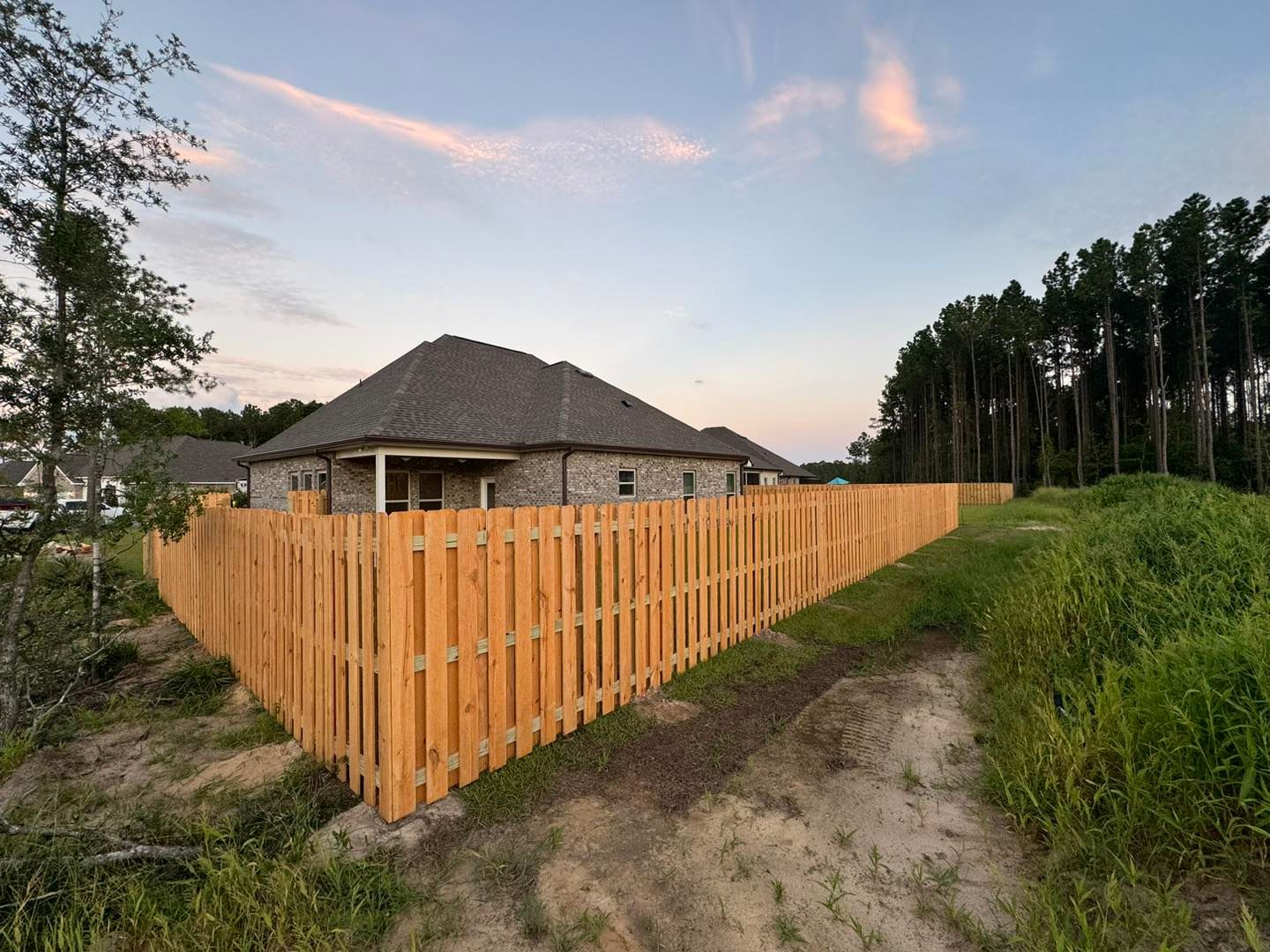 A wooden fence surrounds a house in a residential area.