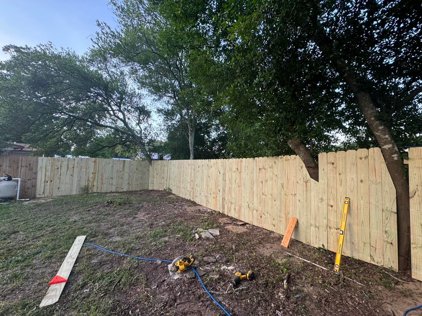 A wooden fence is being built in a backyard.