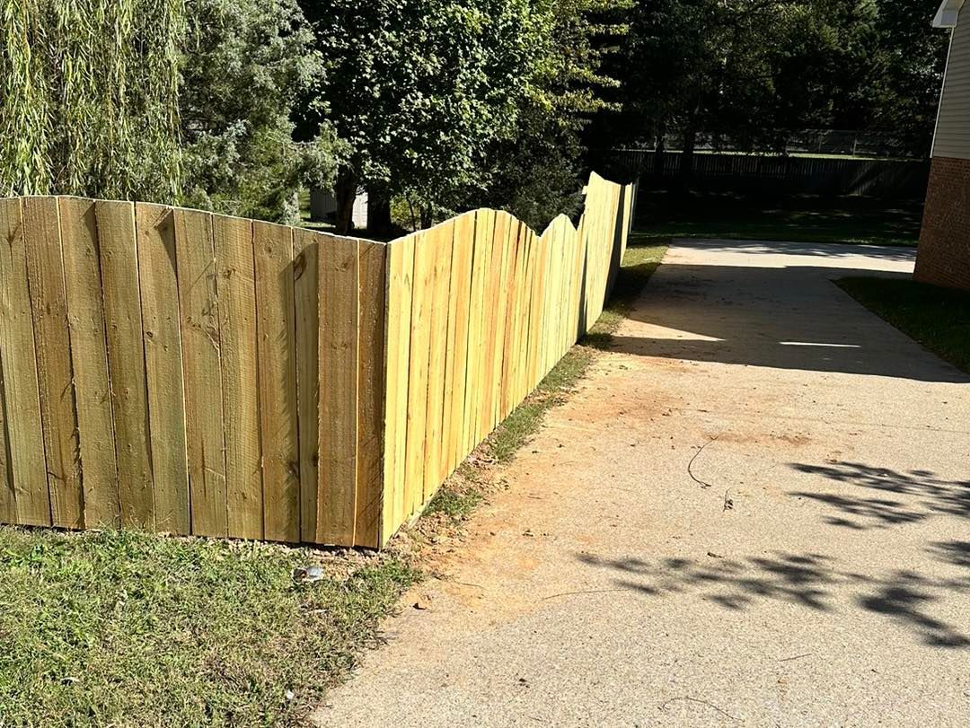 A wooden fence is along the side of a driveway.