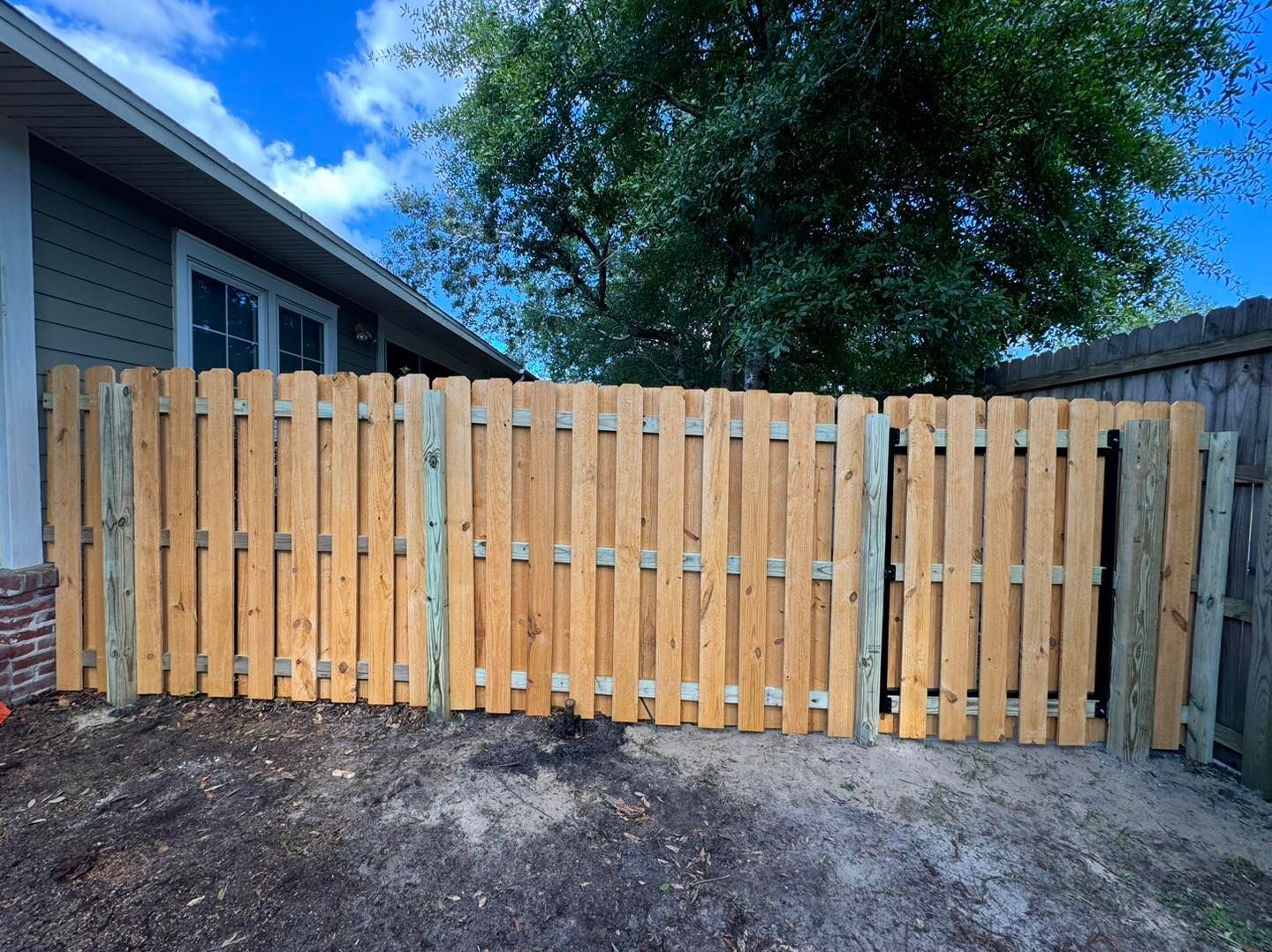 A wooden fence is sitting in front of a house.