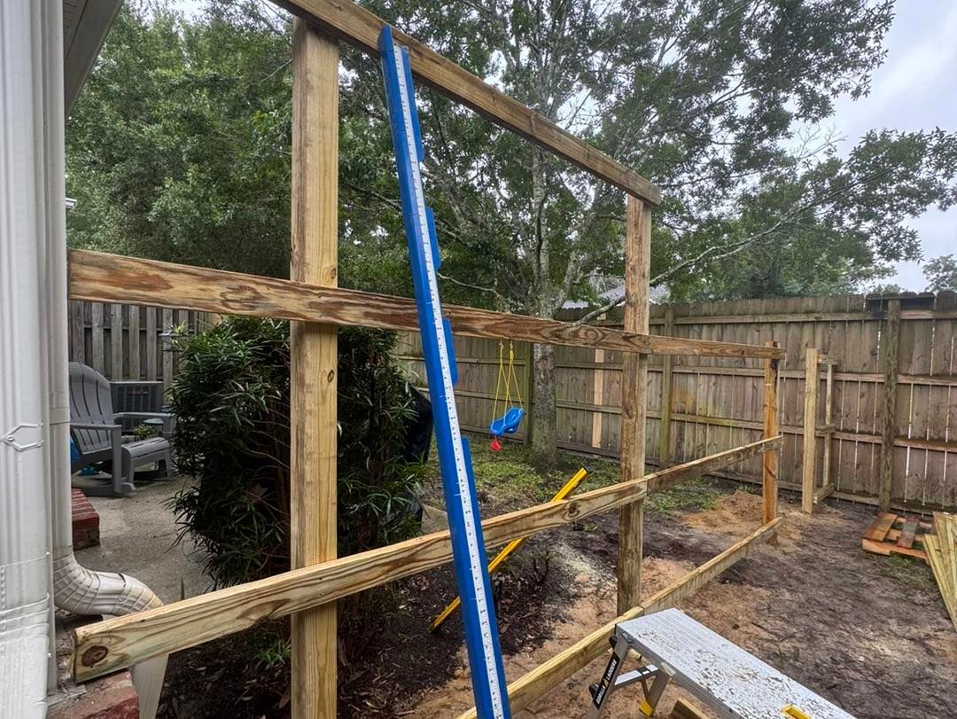 A wooden fence is being built in a backyard.