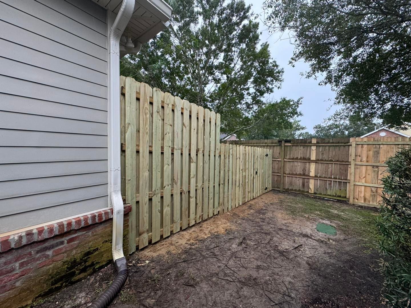 A wooden fence is in the backyard of a house.