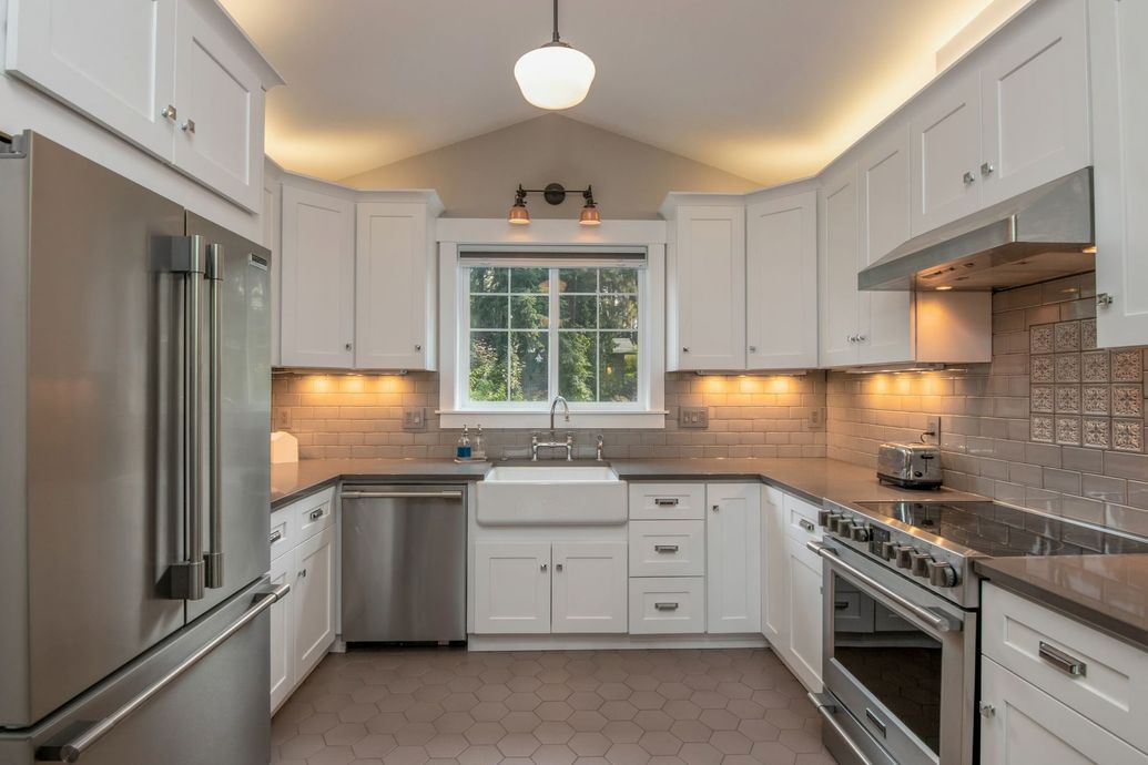 Bright modern kitchen with white cabinets, stainless appliances, and a window over the sink