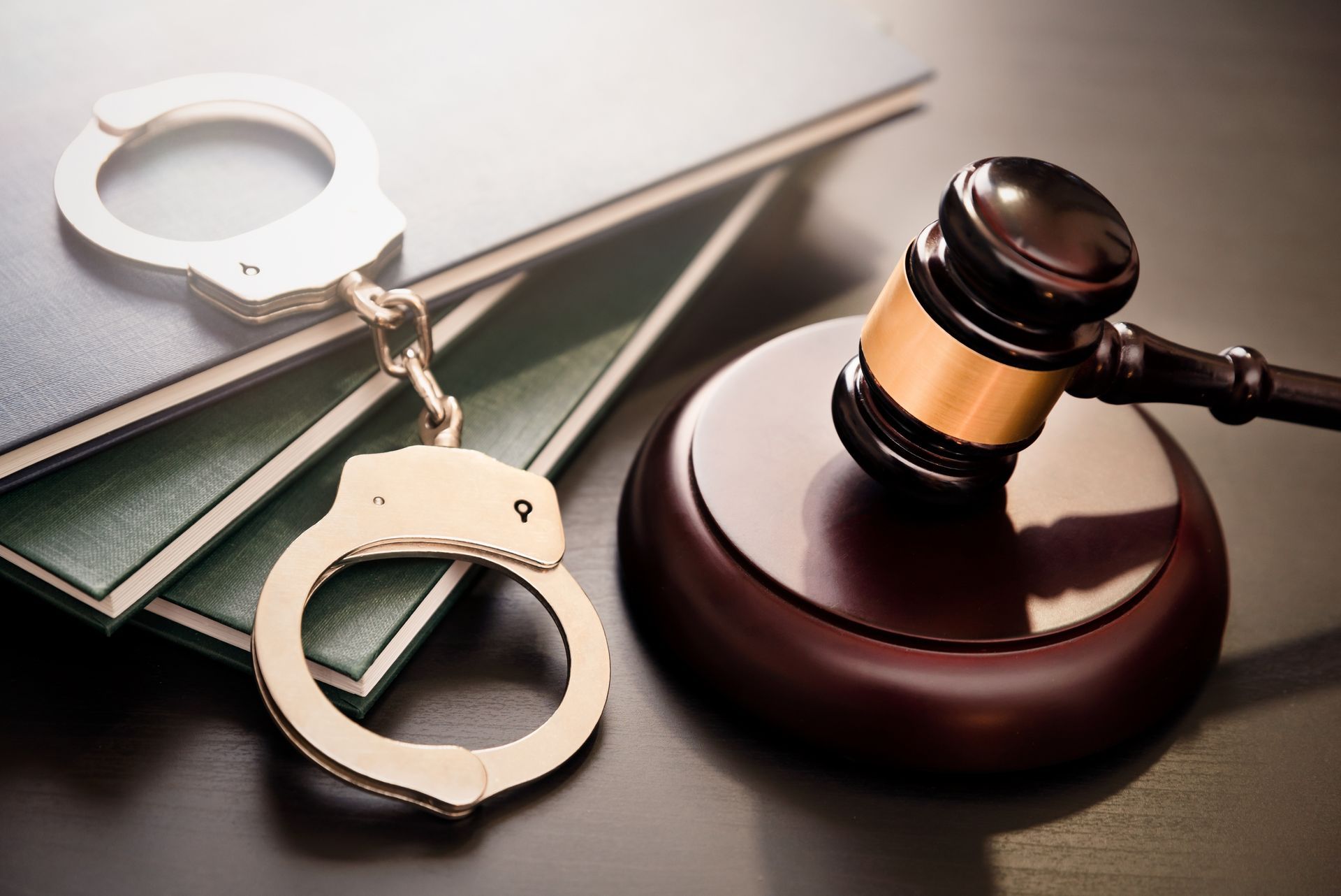 A pair of handcuffs sitting on top of a stack of books next to a judge 's gavel.