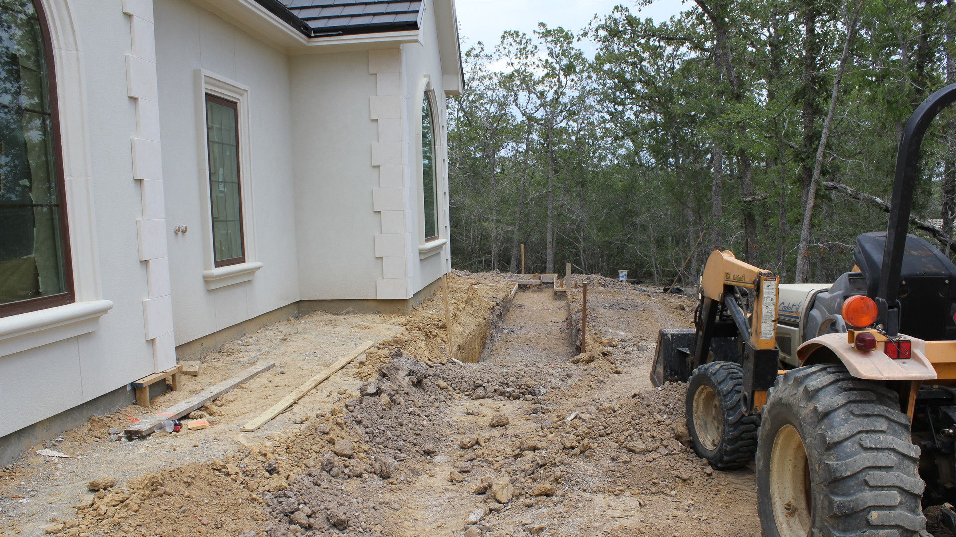A tractor is parked in front of a house under construction.
