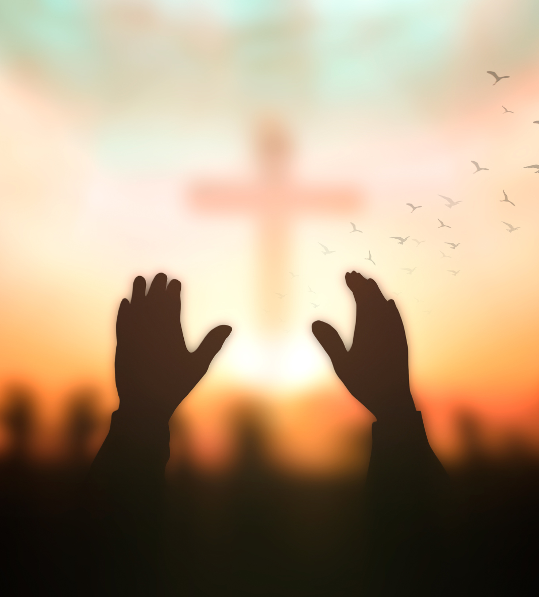 a silhouette of a person's hands with a cross in the background.