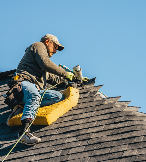 a man is sitting on top of a roof working on it.
