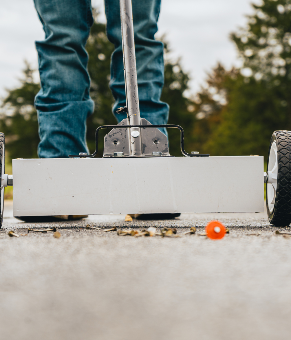 a person is using a magnet sweeper to clean up roofing nails.