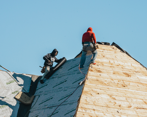 two men are working on the roof of a house.