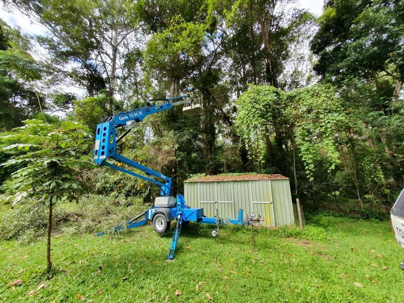 A Blue Aerial Lift is Sitting on Top of a Lush Green Field — Arbaron Pty Ltd in Black Mountain, QLD