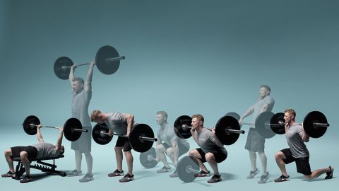 A man is squatting down while lifting a barbell.