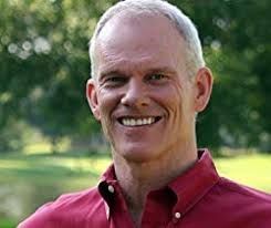 A man in a red shirt is smiling for the camera.