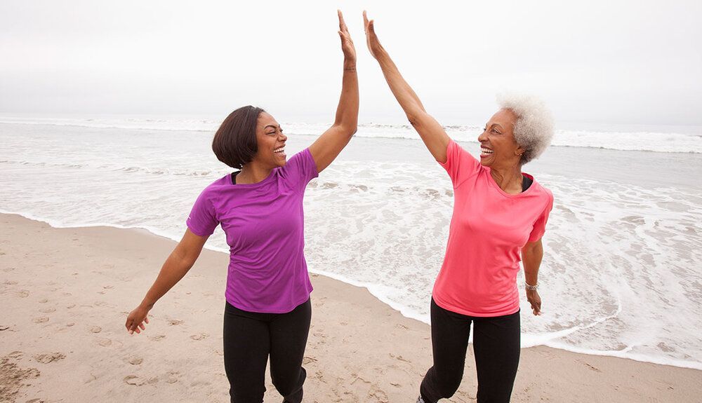 Two women are giving each other a high five on the beach.