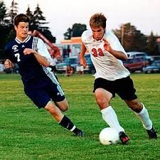 Two men are playing soccer on a field.