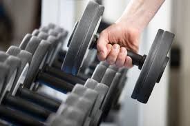 A person is holding a dumbbell in a gym.