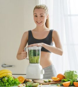 A woman is using a blender to make a smoothie.