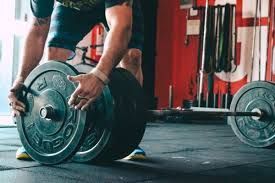 A man is lifting a barbell in a gym.