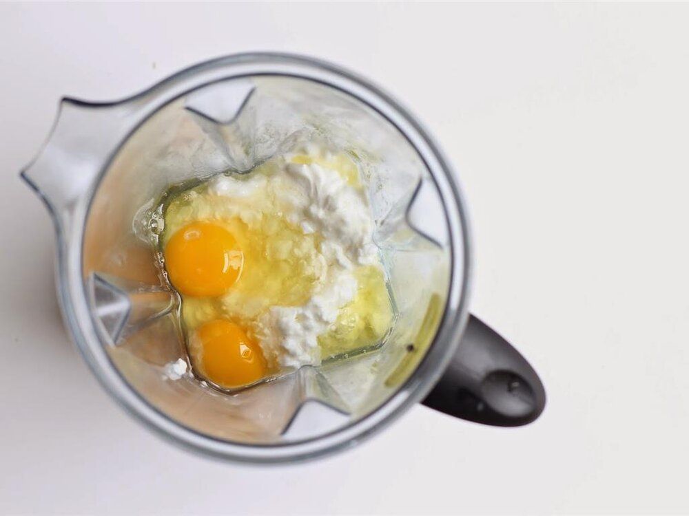 A blender filled with eggs , butter , and flour.