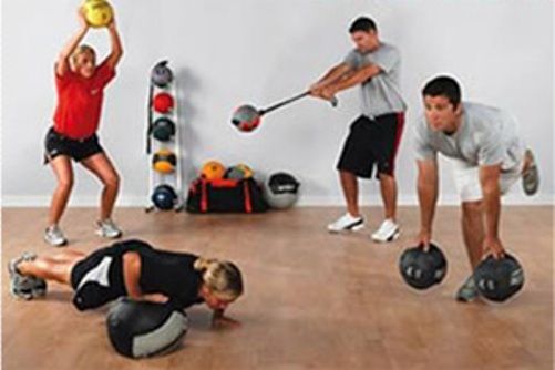 A group of people are doing exercises with balls in a gym