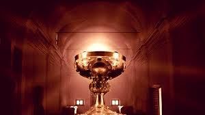 A large gold chalice is sitting in a dark room.