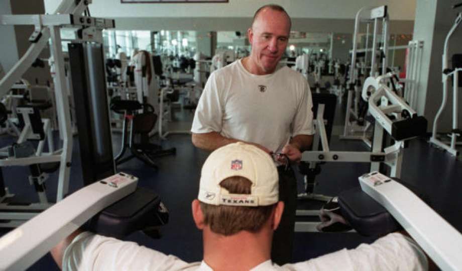 A man wearing a texans hat is working out in a gym