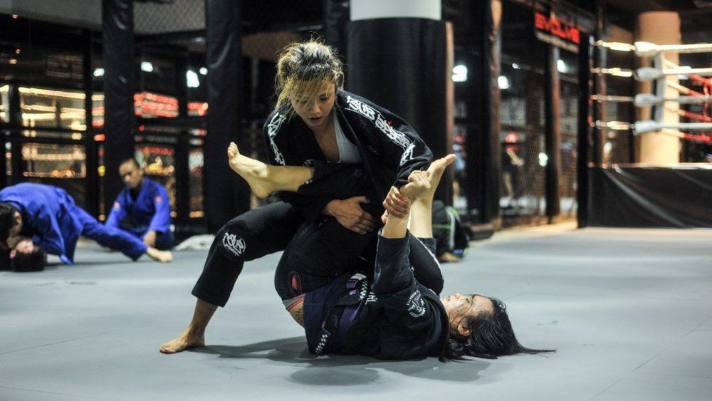 A group of women are practicing jiu jitsu in a gym.