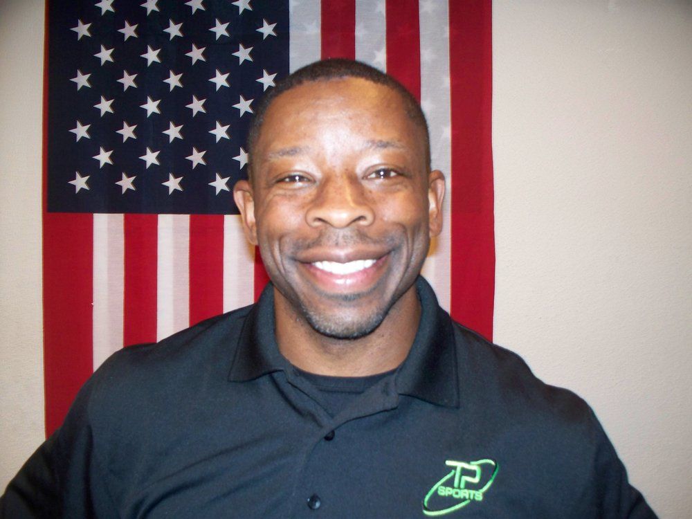 A man is smiling in front of an american flag