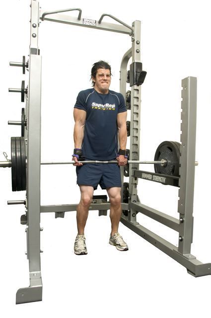 A man is lifting a barbell in a squat rack