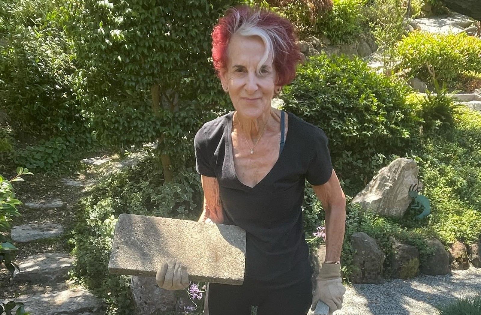 A woman with red hair is holding a large rock in her hands.