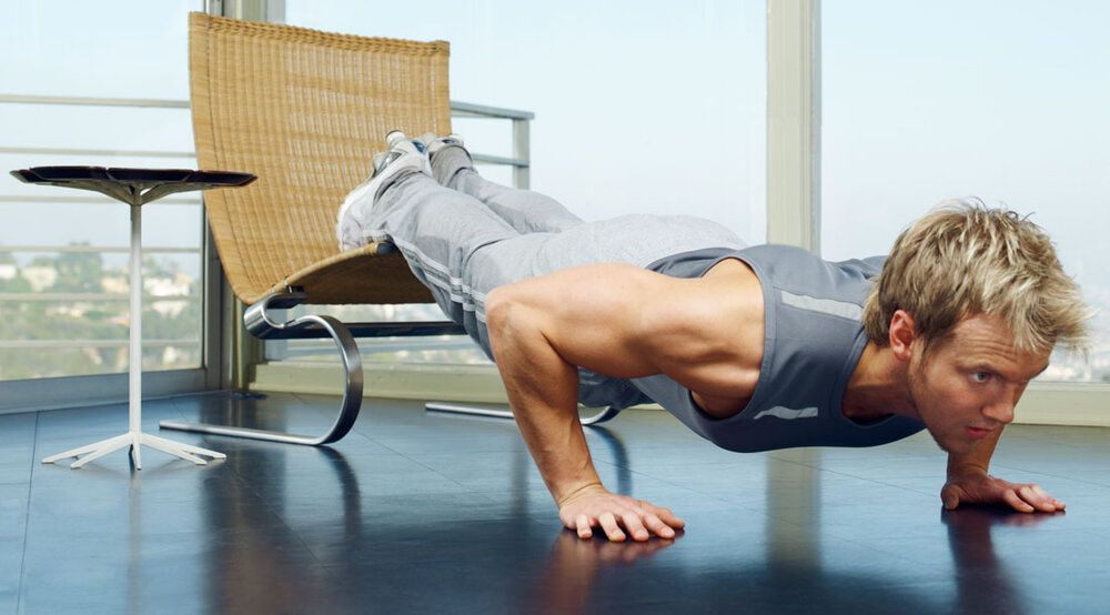 A man is doing push ups on the floor in a living room