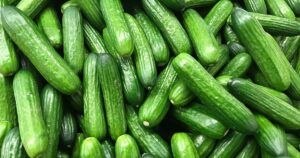 A pile of green cucumbers sitting on top of each other on a table.