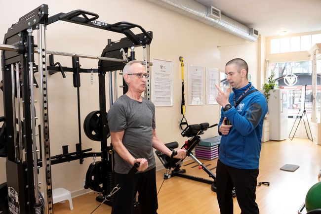 A man is talking to another man in a gym.