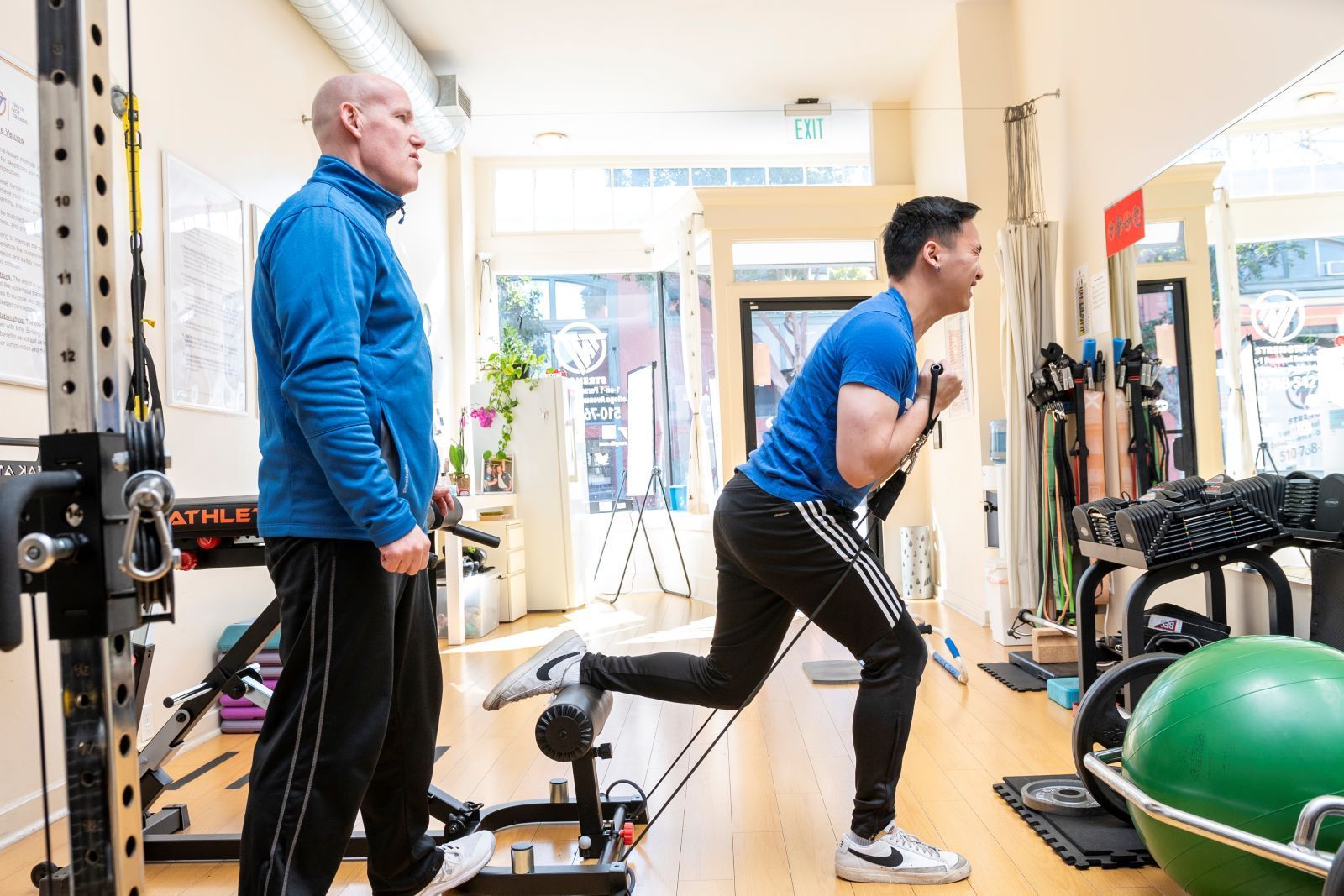 Two men are doing exercises in a gym.