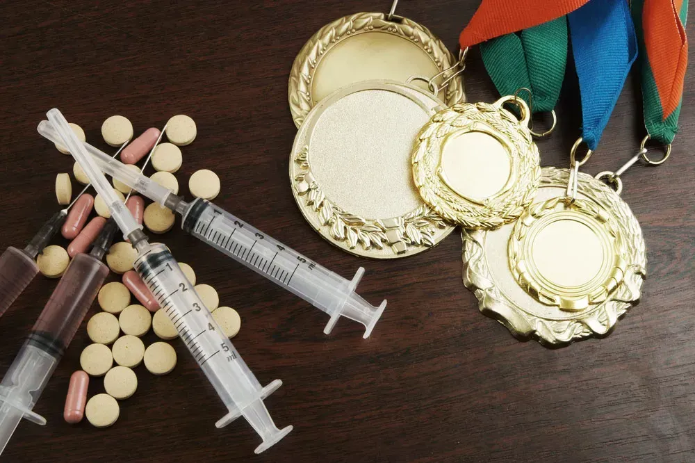 Picture of athletic medal juxtaposed with pills and a syringe signifying doping