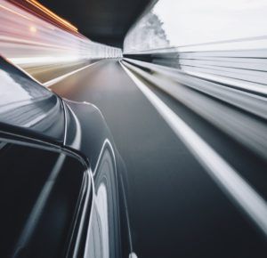 A car is driving through a tunnel on a highway.