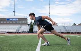 A man is running on a track in a stadium.