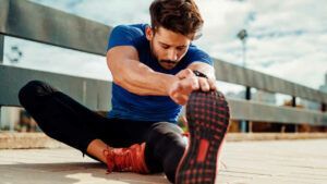 A man is sitting on the ground stretching his legs.