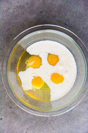 Eggs , milk , and oil are in a glass bowl.