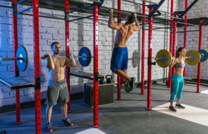 A group of people are doing pull ups in a gym.