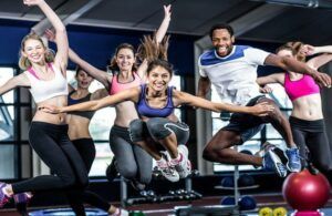 A group of people are jumping in the air in a gym.