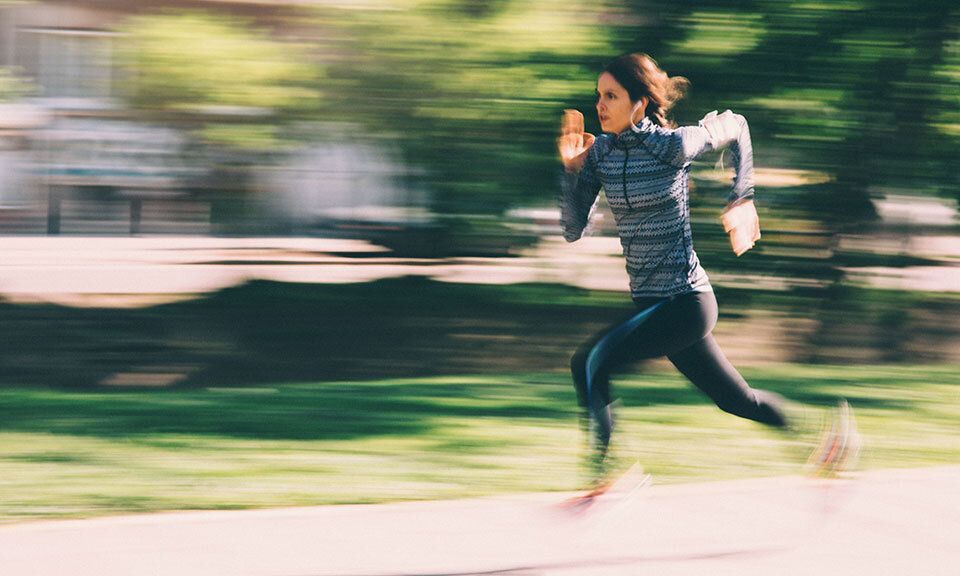 A woman is running in a park in a blurry photo.