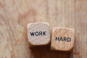 Two wooden dice with the words work and hard written on them.