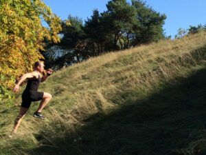 A man is running up a grassy hill.