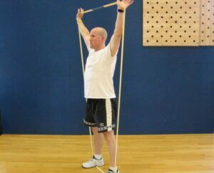 A man is holding a resistance band over his head.